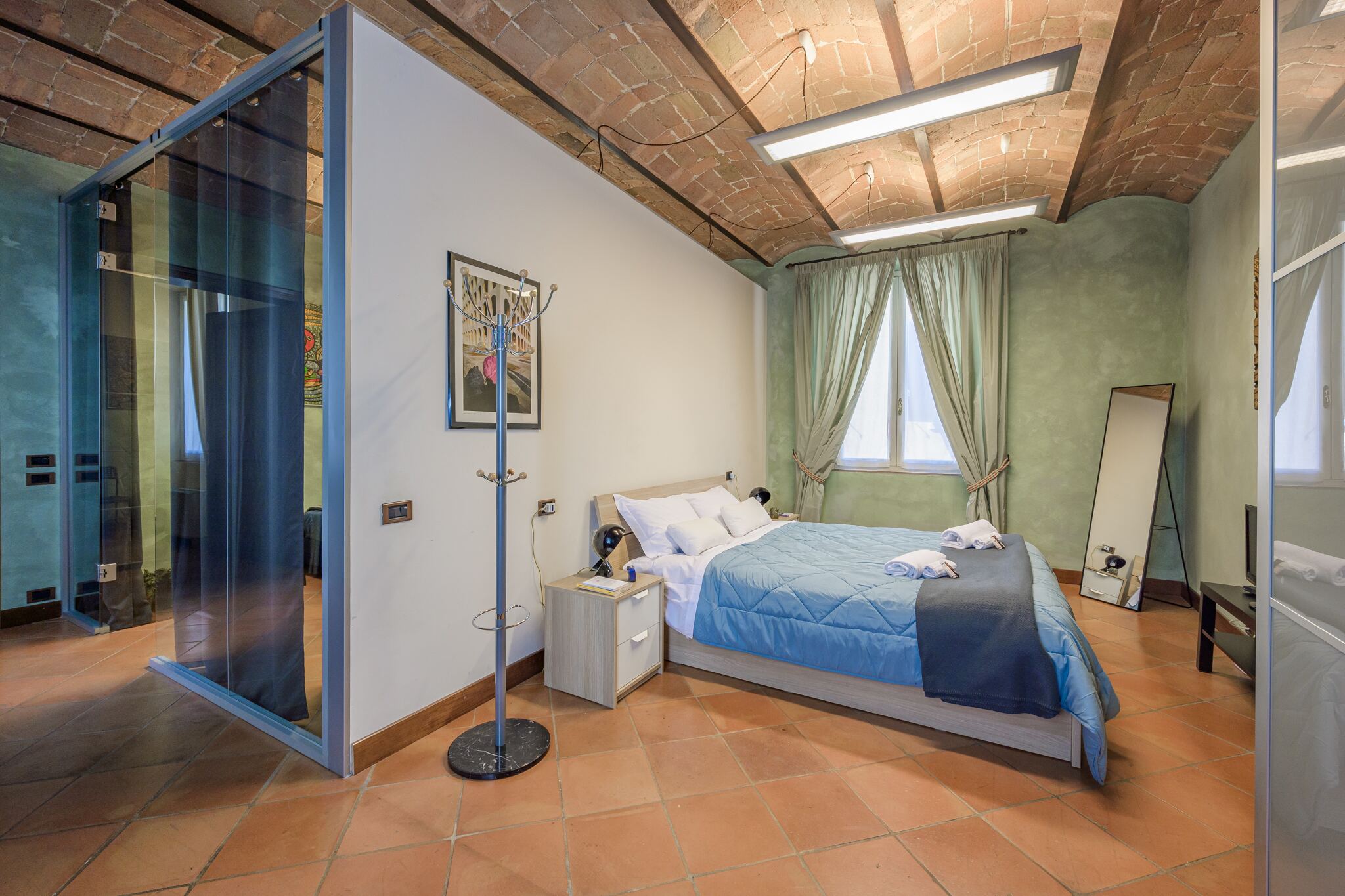 La camera matrimoniale con la parete in vetro e il letto con la coperta blu