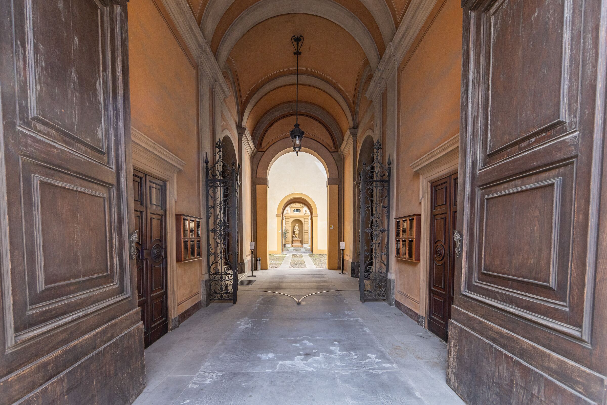 L'androne di Palazzo Montecuccoli, con le volte, i cancelli in ferro battuto e il cortile in fondo