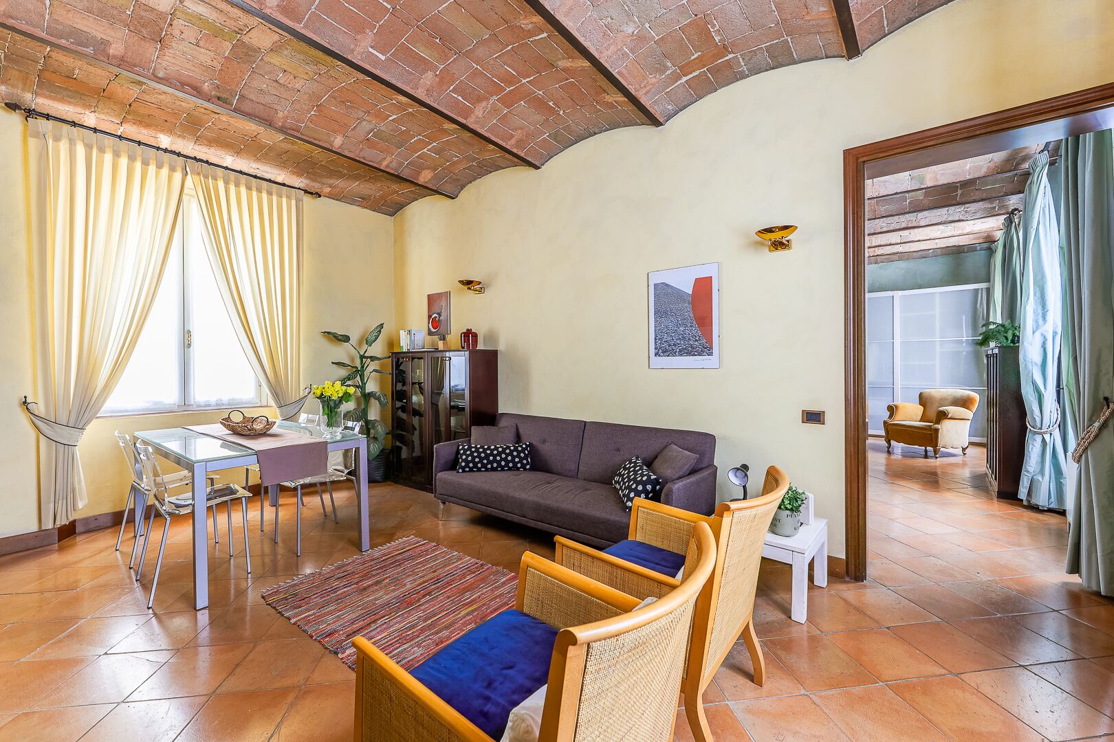 Il soggiorno visto dalla zona pranzo, con il divano e le finestre sulla città